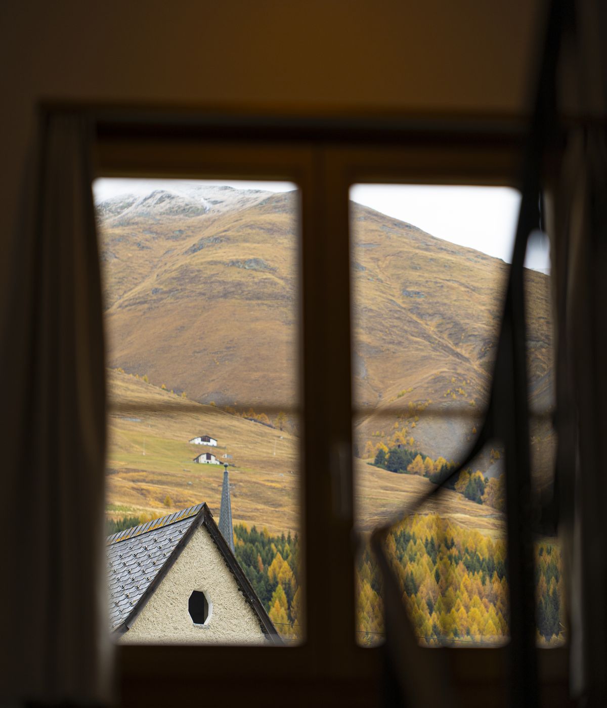 Autumn larches and mountains near Zuoz, seen through a window