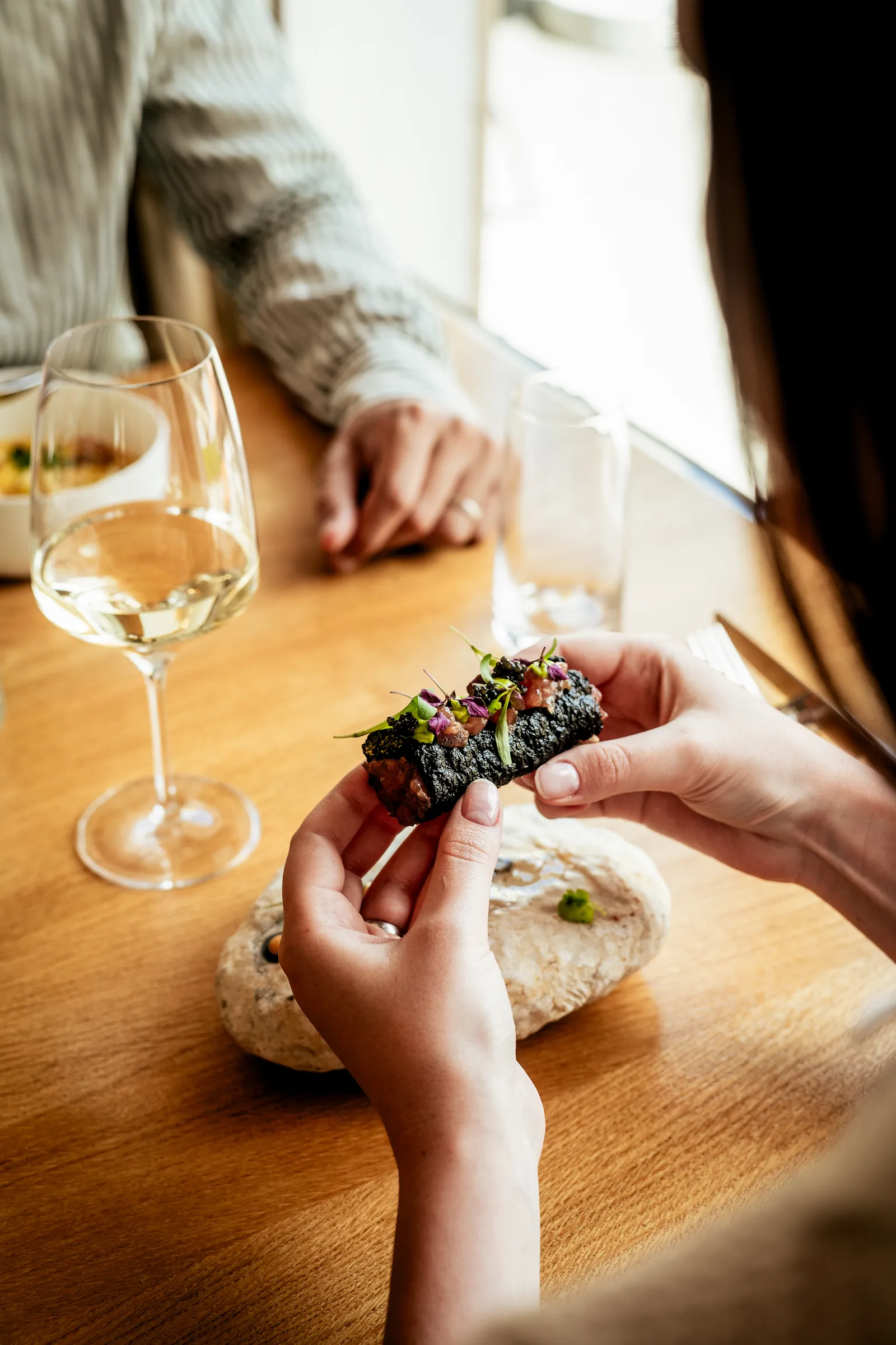 Ospiti al tavolo con taco di nori e vino bianco