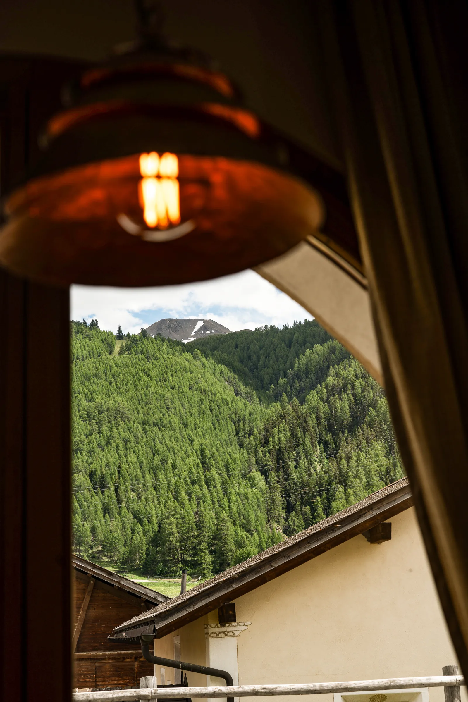 Lampada e finestra ad arco sul bosco di larici