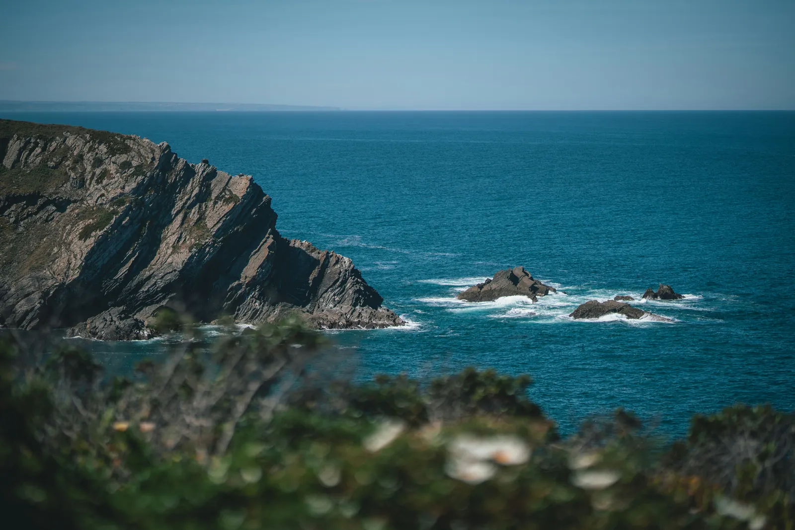 Felsküste in der Brandung, tiefblaues Meer bis zum Horizont