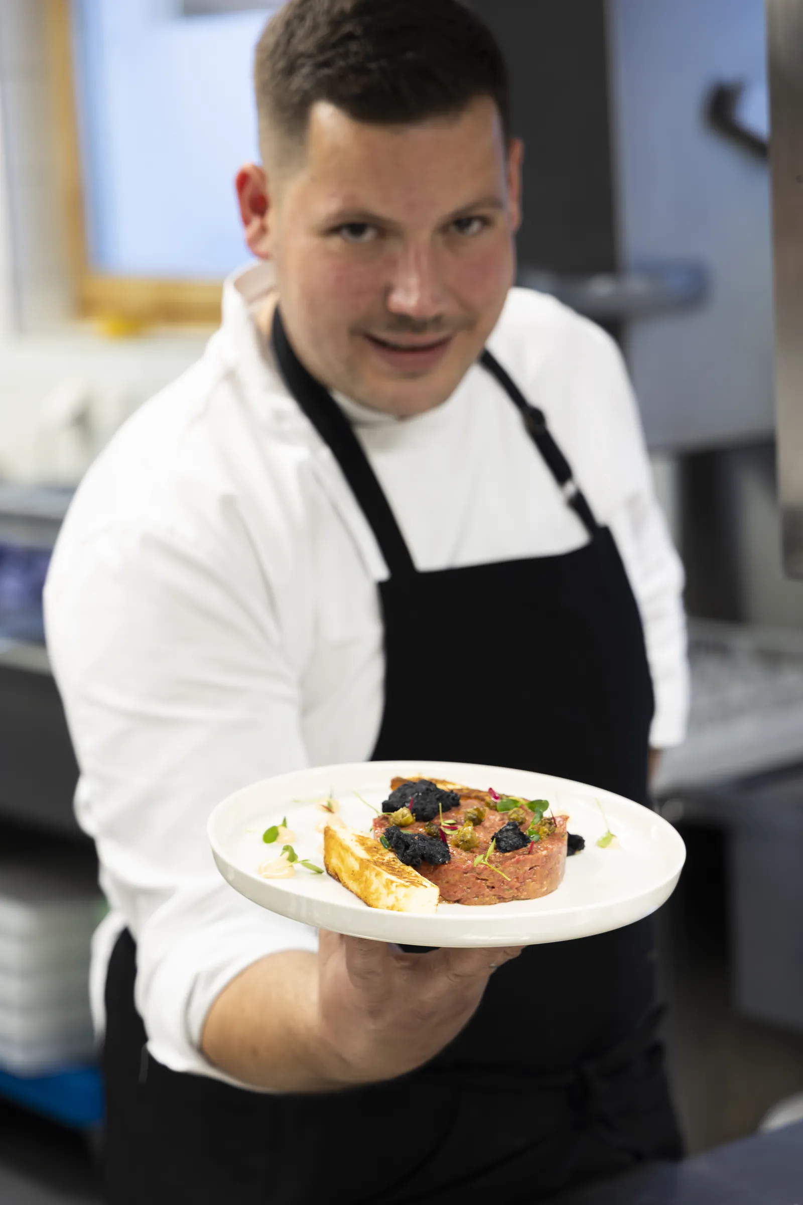 El chef David Arellano con un plato en la cocina de Alegría